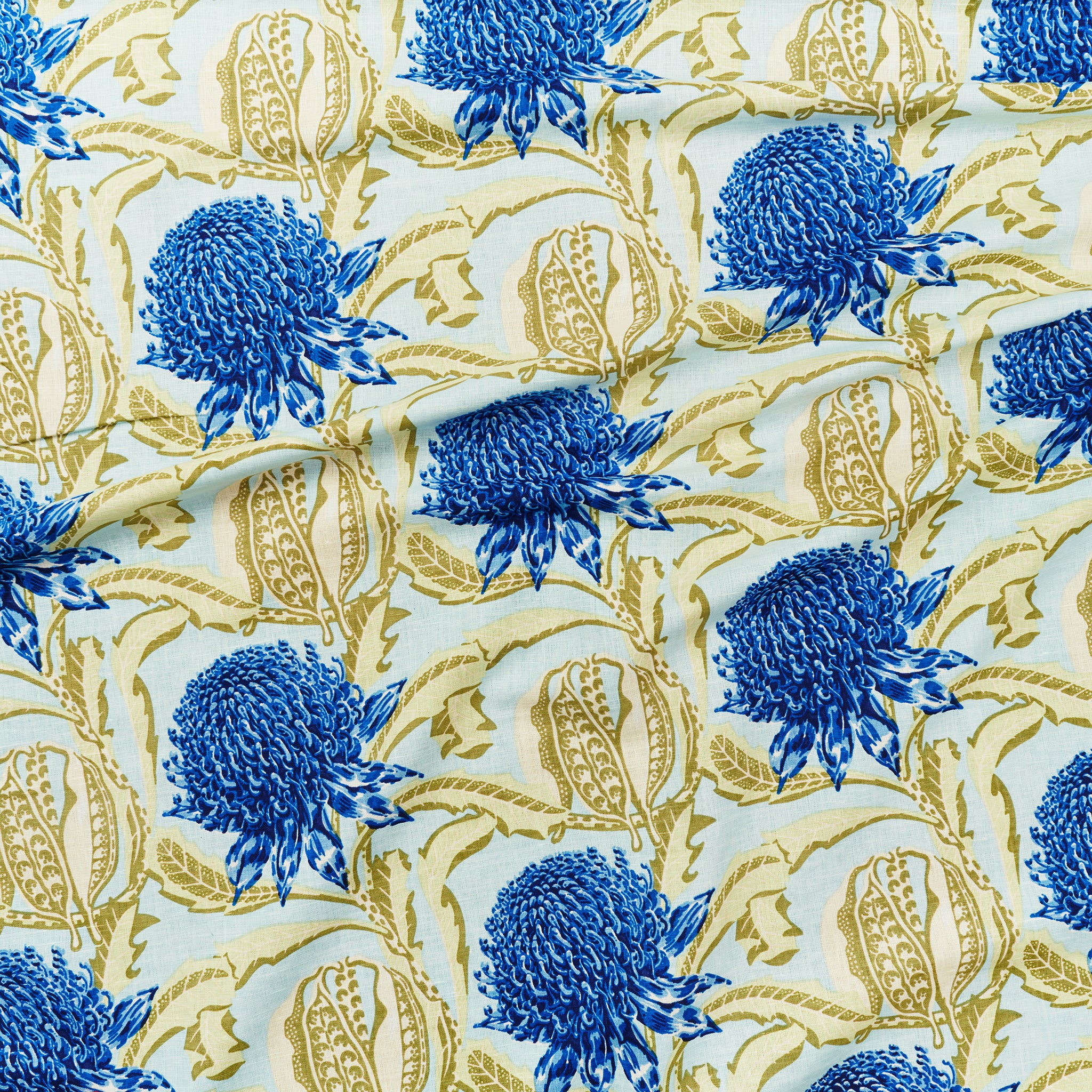 Draped fabric in a large-scale floral print in shades of royal blue and soft green on an acqua field.
