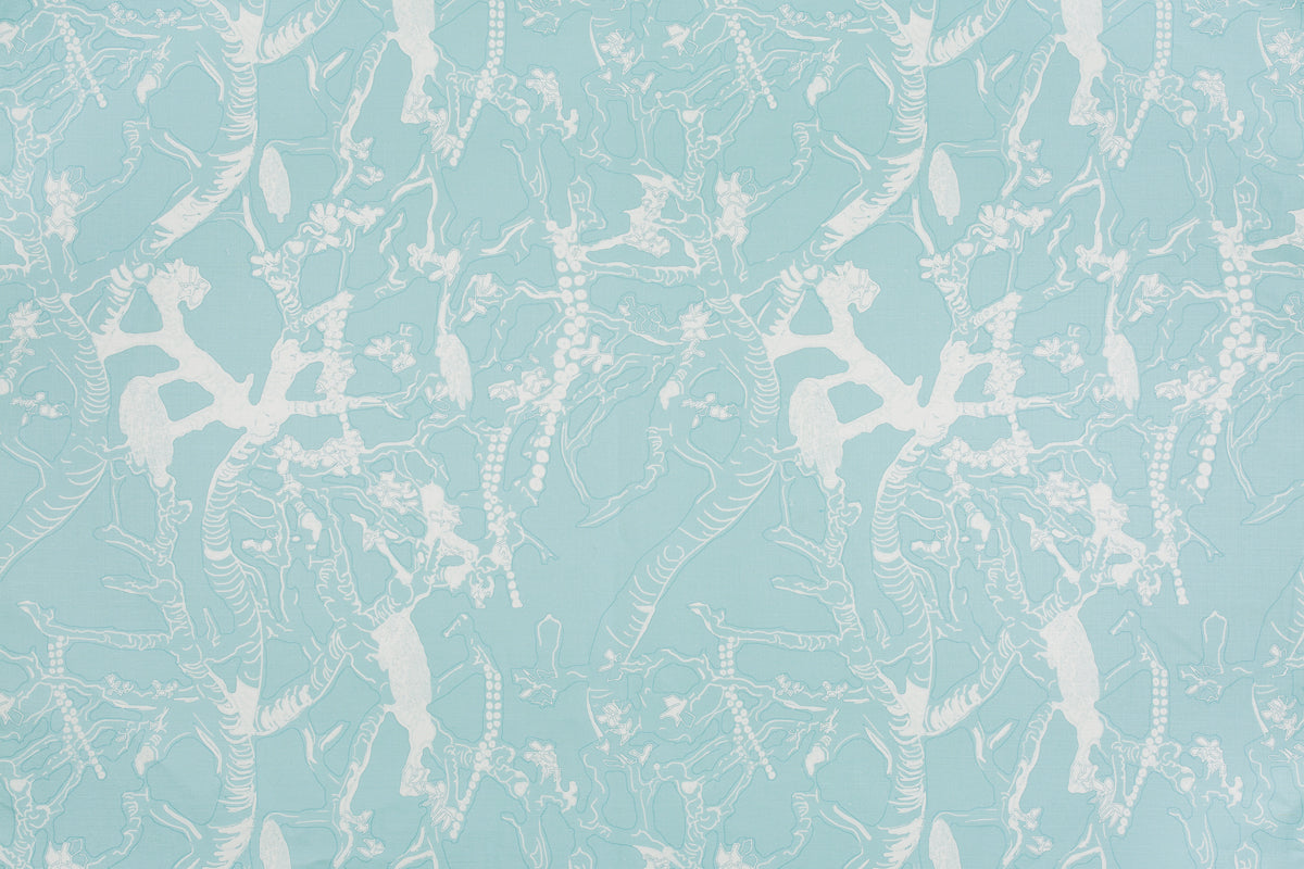 Detail of fabric in a branch and blossom print in cream and blue on a light blue field.