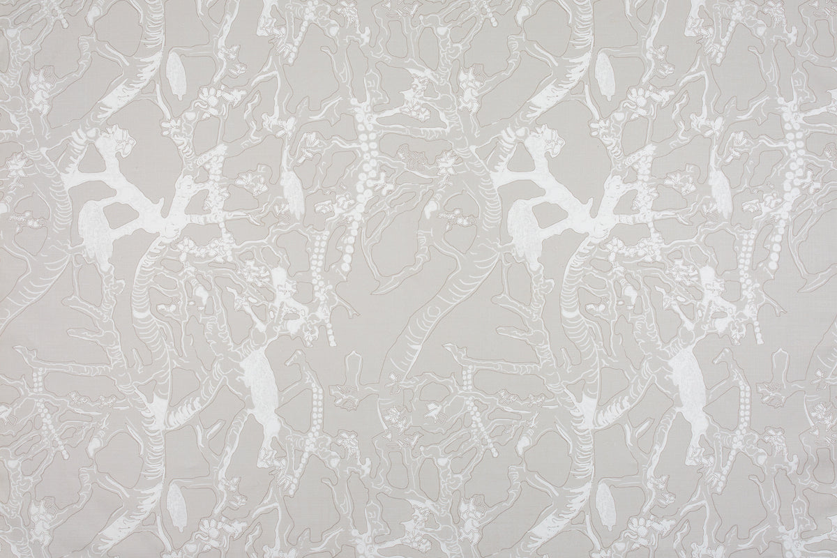 Detail of fabric in a branch and blossom print in white and gray on a light gray field.