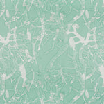Detail of fabric in a branch and blossom print in white and green on a light green field.