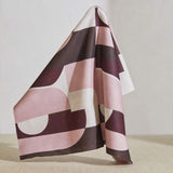 A large piece of draped fabric in a curvilinear geometric print in pink and maroon on a white field.
