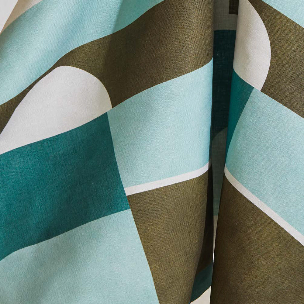 Draped fabric yardage in a curvilinear geometric print in blue, turquoise and sage on a white field.