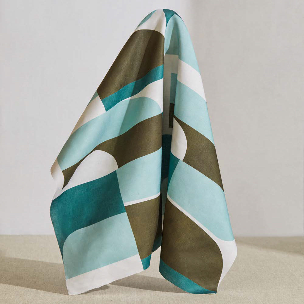 A large piece of draped fabric in a curvilinear geometric print in blue, turquoise and sage on a white field.