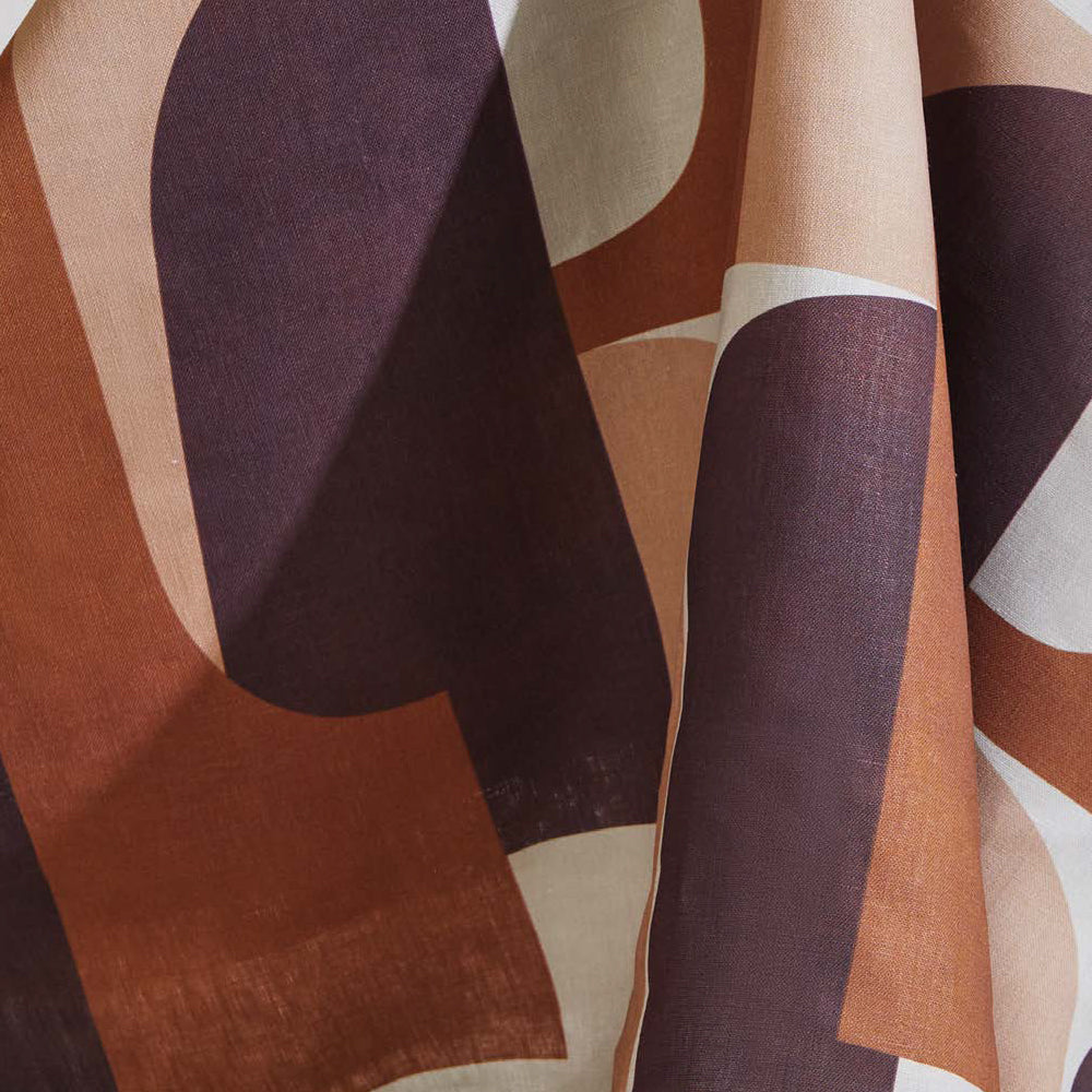Draped fabric yardage in a curvilinear geometric print in peach, purple and rust on a white field.