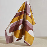 A large piece of draped fabric in a curvilinear geometric print in purple, maroon and mustard on a white field.
