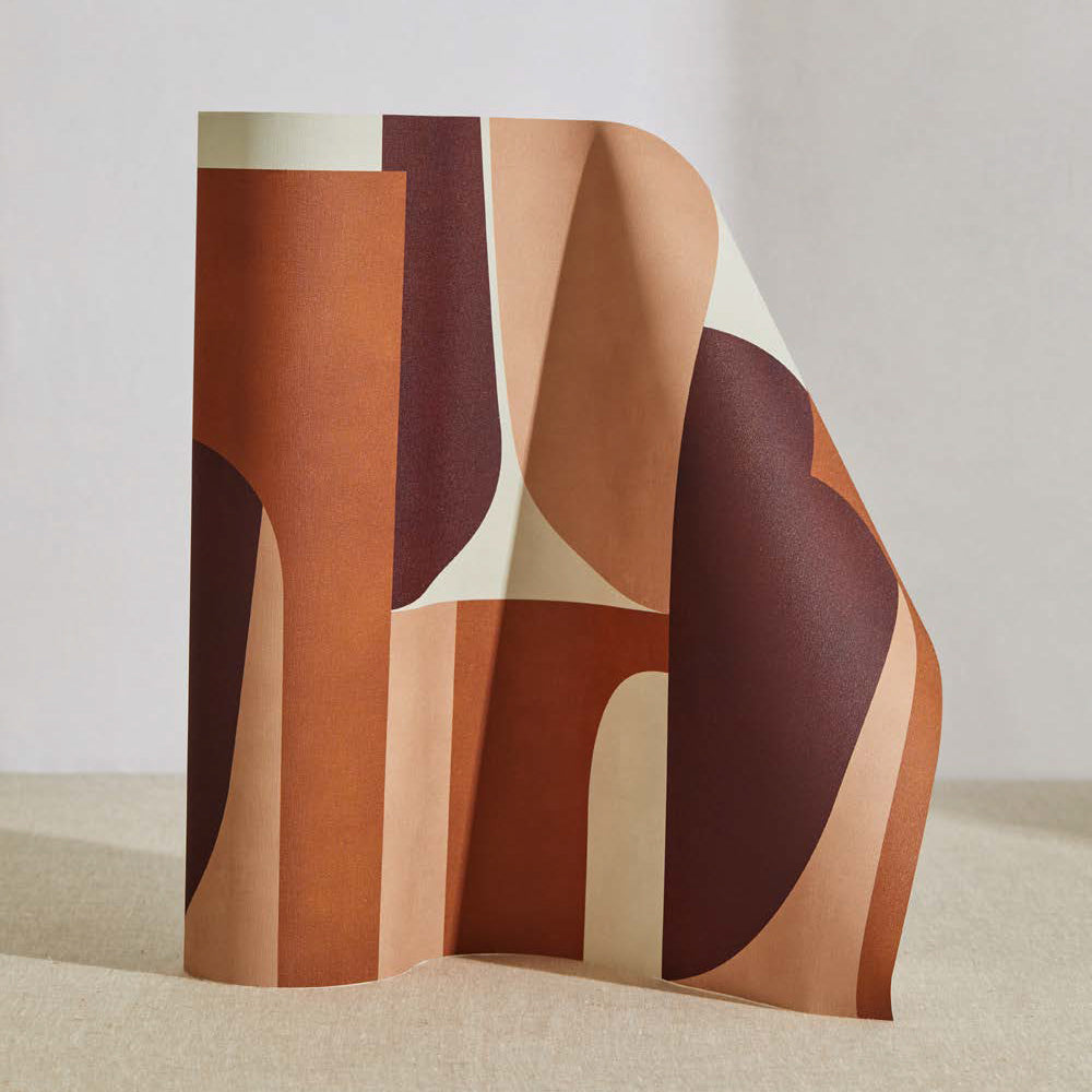 A curved partition stands on the ground, covered in a curvilinear geometric grid print in shades of rust, peach and cream.