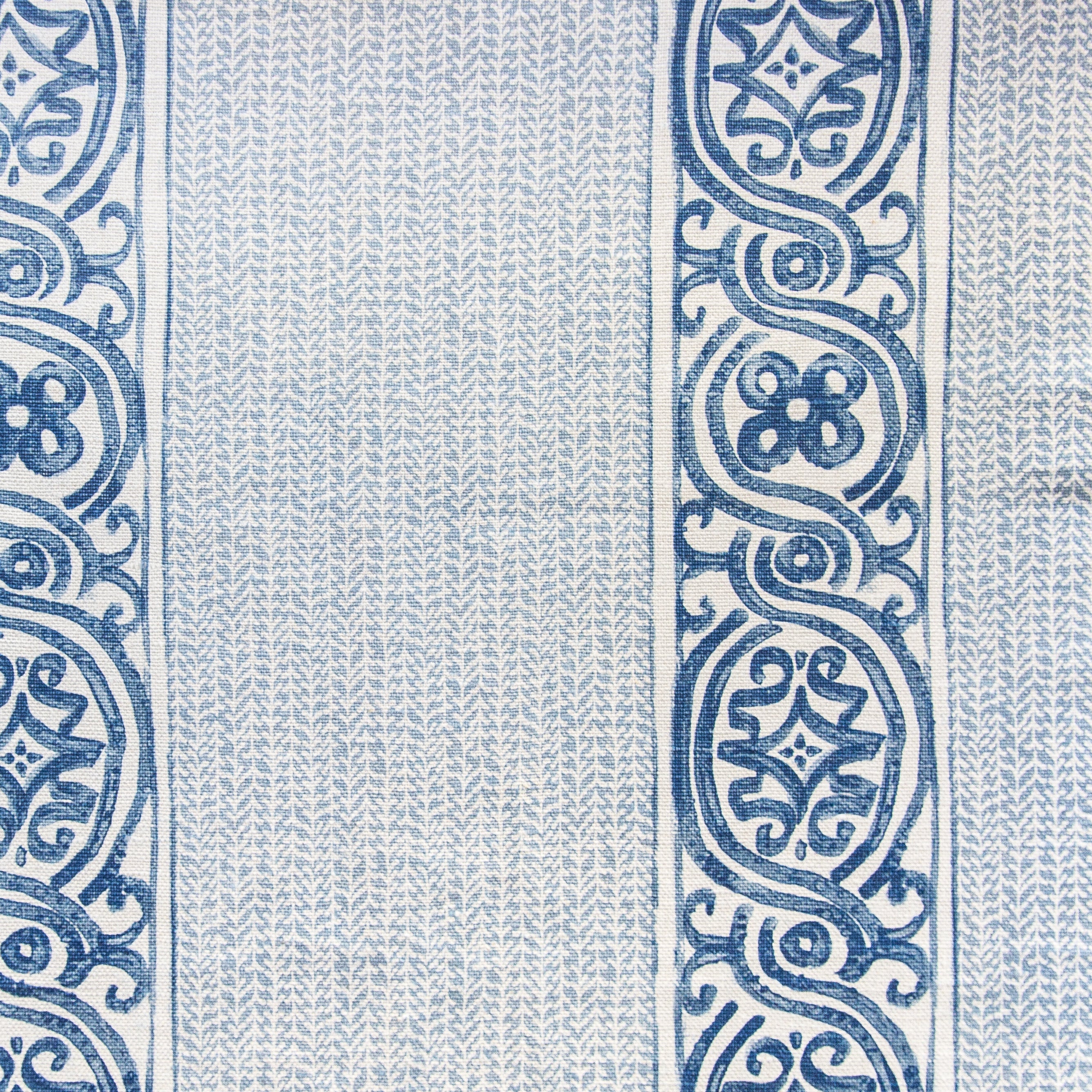 Detail of fabric in a painterly stripe print in navy and blue on a cream field.