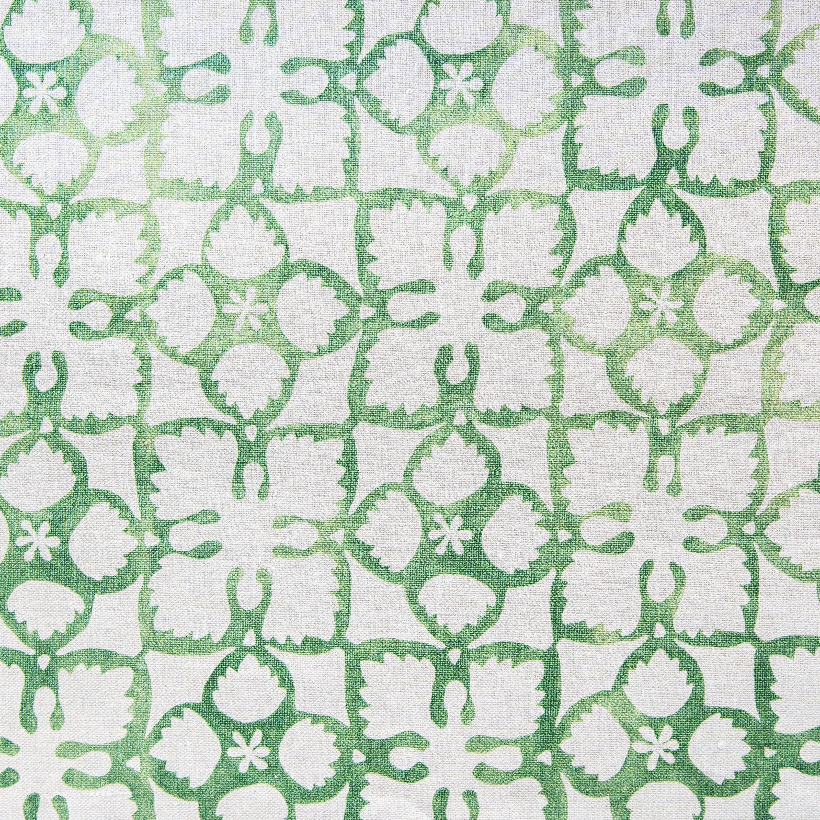 Detail of fabric in a botanical lattice print in green on a white field.