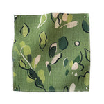 Square fabric swatch in a painterly leaf print in shades of green and white on a kelly green field.