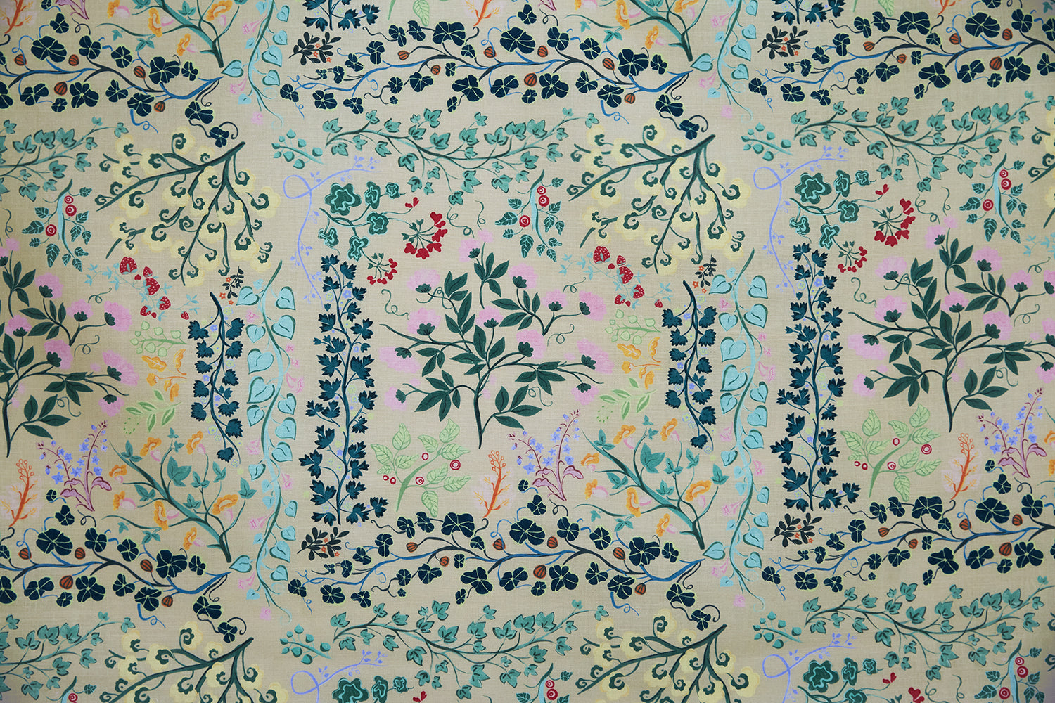 Detail of fabric in a dense floral print in shades of pink, yellow, green and black on a tan field.