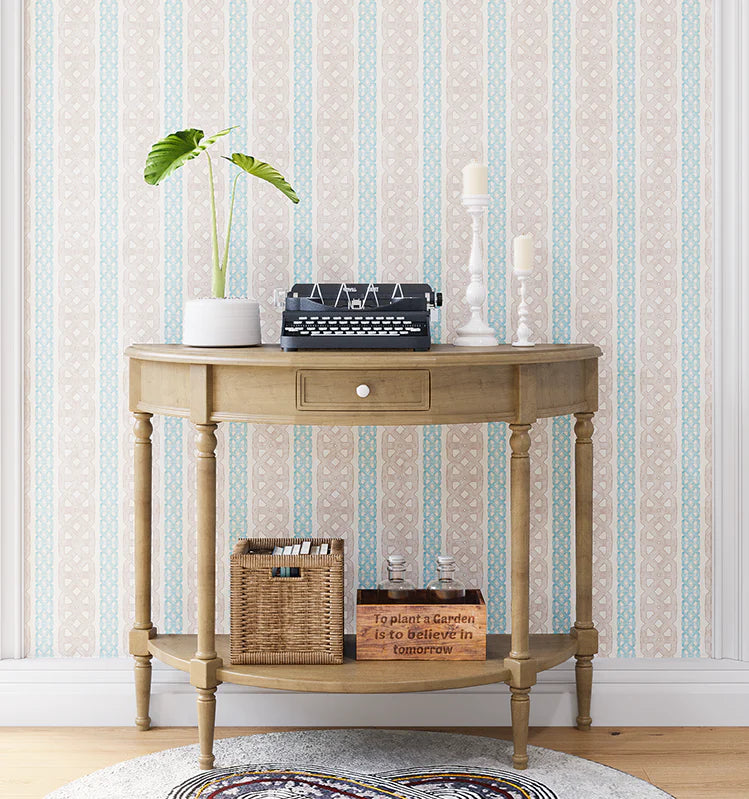 A styled end table stands in front of a wall papered in a geometric stripe print in blue, tan and cream.