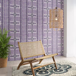 Styled living room tableau with a wall papered in a geometric stripe print in purple with green accents.