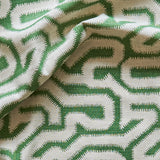 Draped fabric yardage in a playful meandering print in cream on a green field.