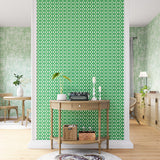 A maximalist living space with an accent wall papered in an intricate lattice print in green on a cream field.