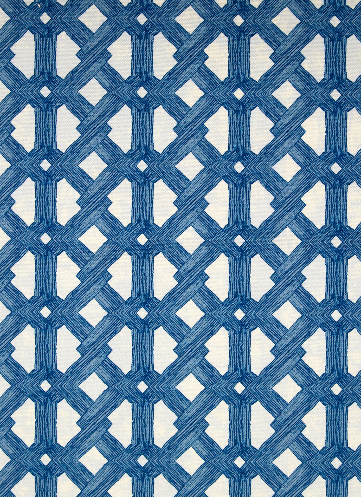 Detail of fabric in an intricate lattice print in navy on a cream field.