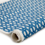 Partially unrolled fabric in an intricate lattice print in navy on a cream field.