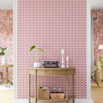 A maximalist living space with an accent wall papered in an intricate lattice print in pink on a cream field.
