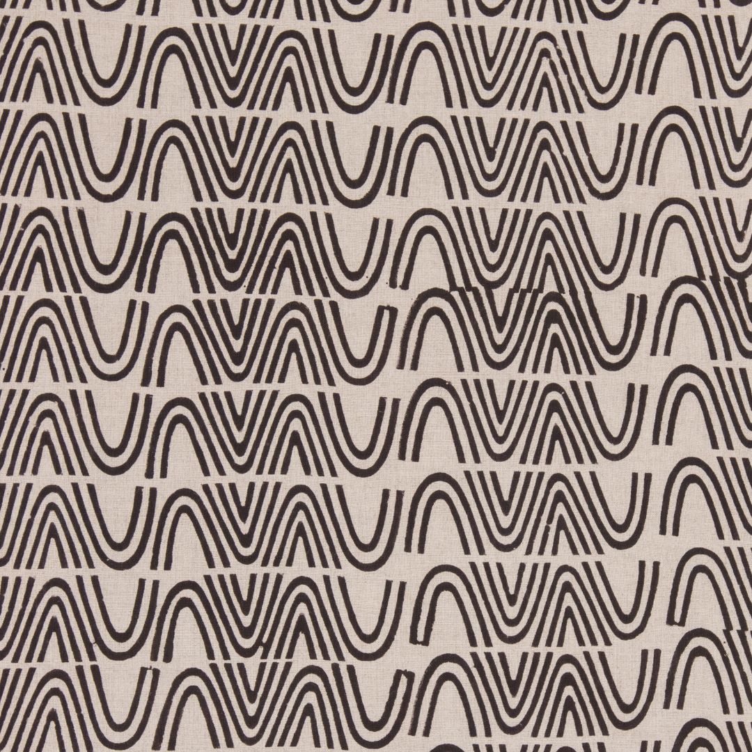 Detail of fabric in an abstract curvilinear stripe in black on a tan field.