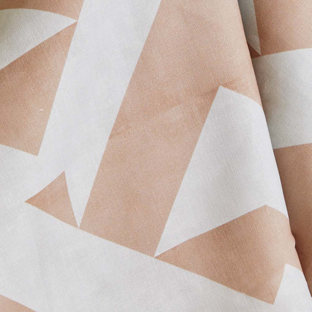 Draped fabric yardage in a large-scale geometric print in peach on a white field.