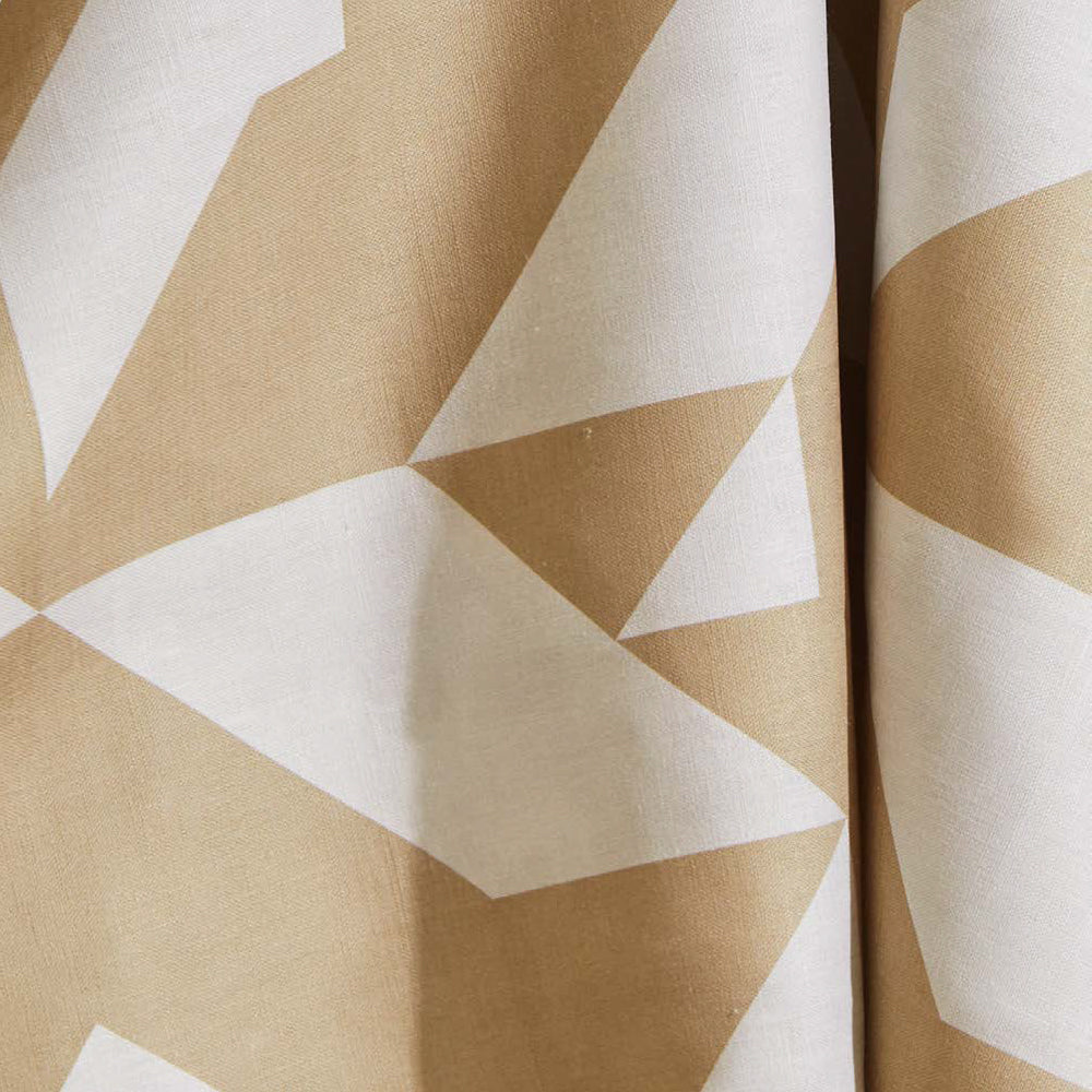 Draped fabric yardage in a large-scale geometric print in tan on a white field.