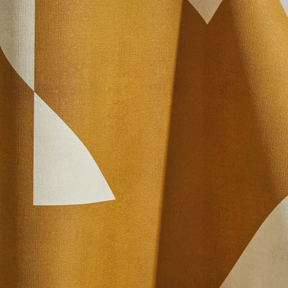 Draped wallpaper yardage in a large-scale geometric print in mustard on a cream field.
