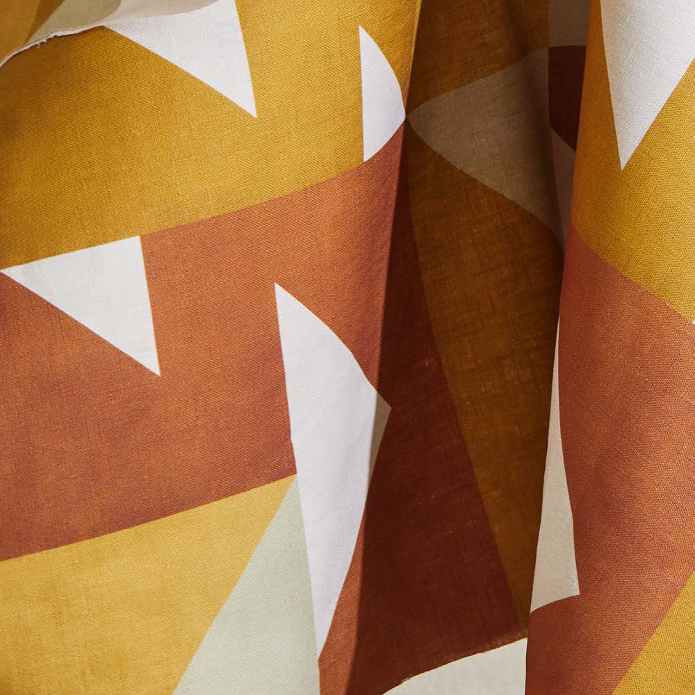 Draped fabric yardage in a large-scale geometric print in orange and rust on a white field.