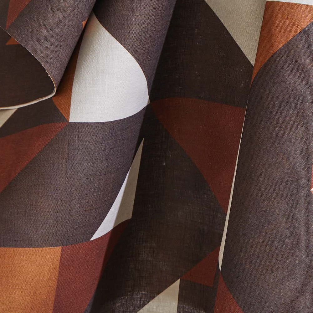 Draped fabric yardage in a large-scale geometric print in rust and brown on a white field.