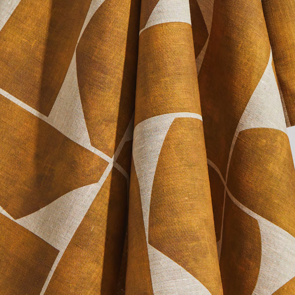 Draped fabric yardage in a large-scale curvilinear geometric print in sienna on a tan field.