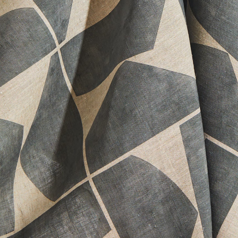 Draped fabric yardage in a large-scale curvilinear geometric print in gray on a cream field.