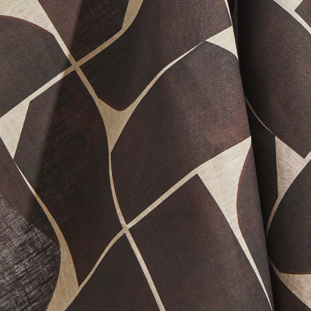 Draped fabric yardage in a large-scale curvilinear geometric print in brown on a cream field.