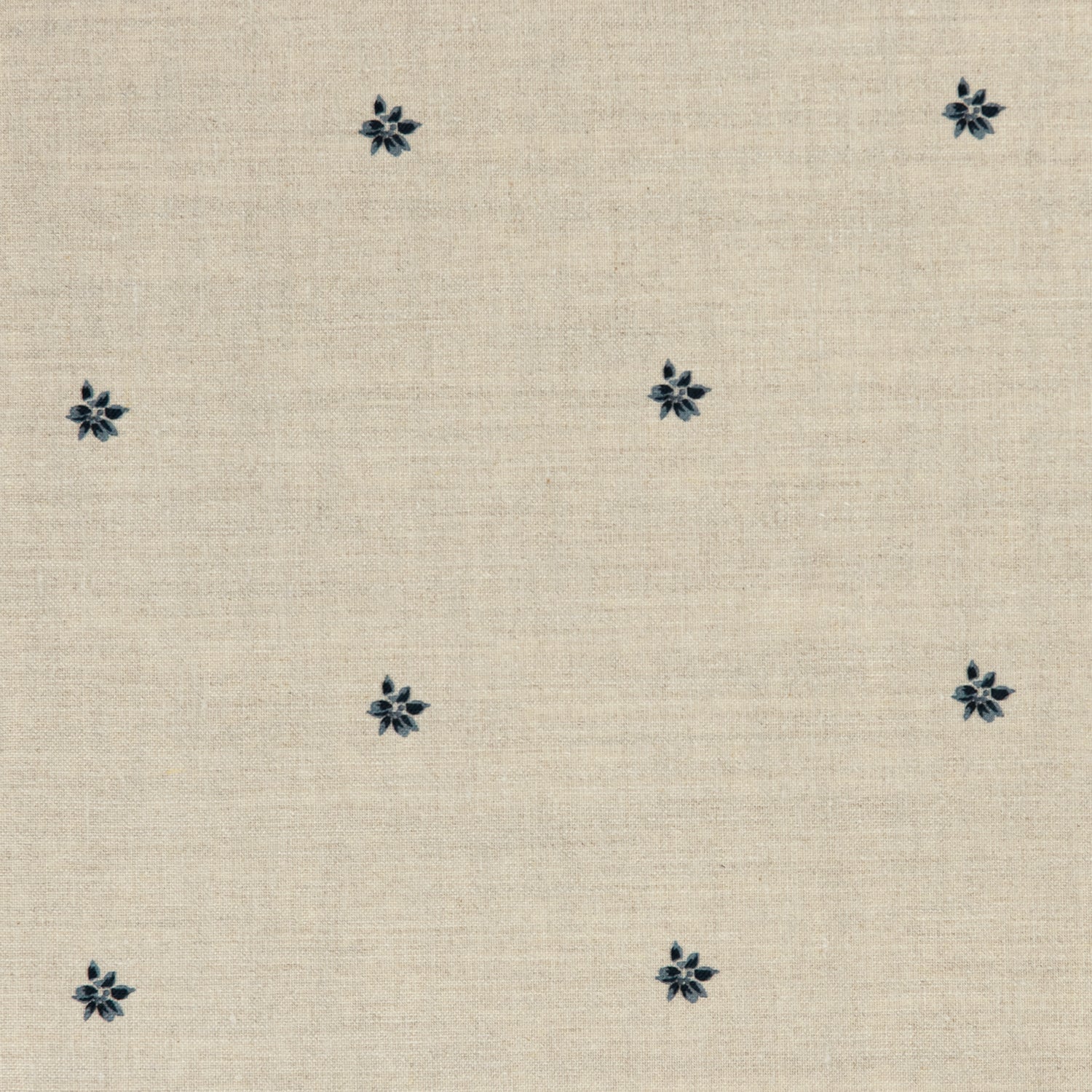 Detail of a printed linen fabric in a repeating small-scale flower pattern in navy on a cream field.