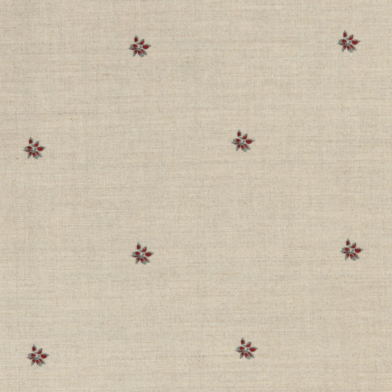 Detail of a printed linen fabric in a repeating small-scale flower pattern in red and gray on a cream field.