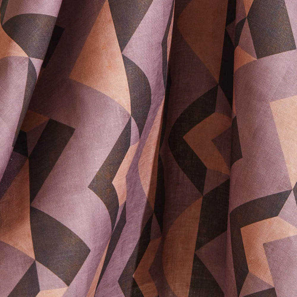 Draped fabric yardage in a dense geometric print in shades of peach, brown and purple.
