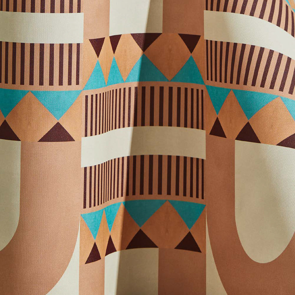 Draped wallpaper yardage in a dense geometric print in shades of blue, peach and purple on a cream field.