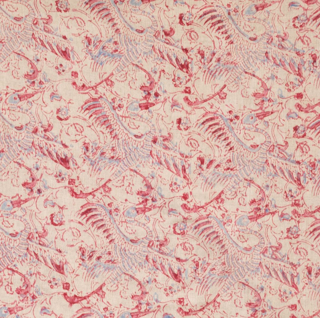 Detail of fabric in intricate flower and crane print in red and light blue on a tan field.