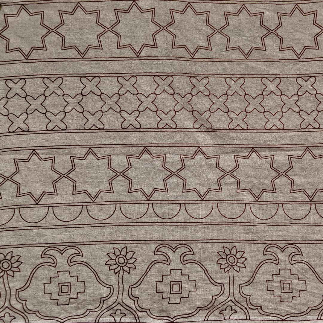 Detail of fabric in an intricate linear lattice print in black on a brown field.