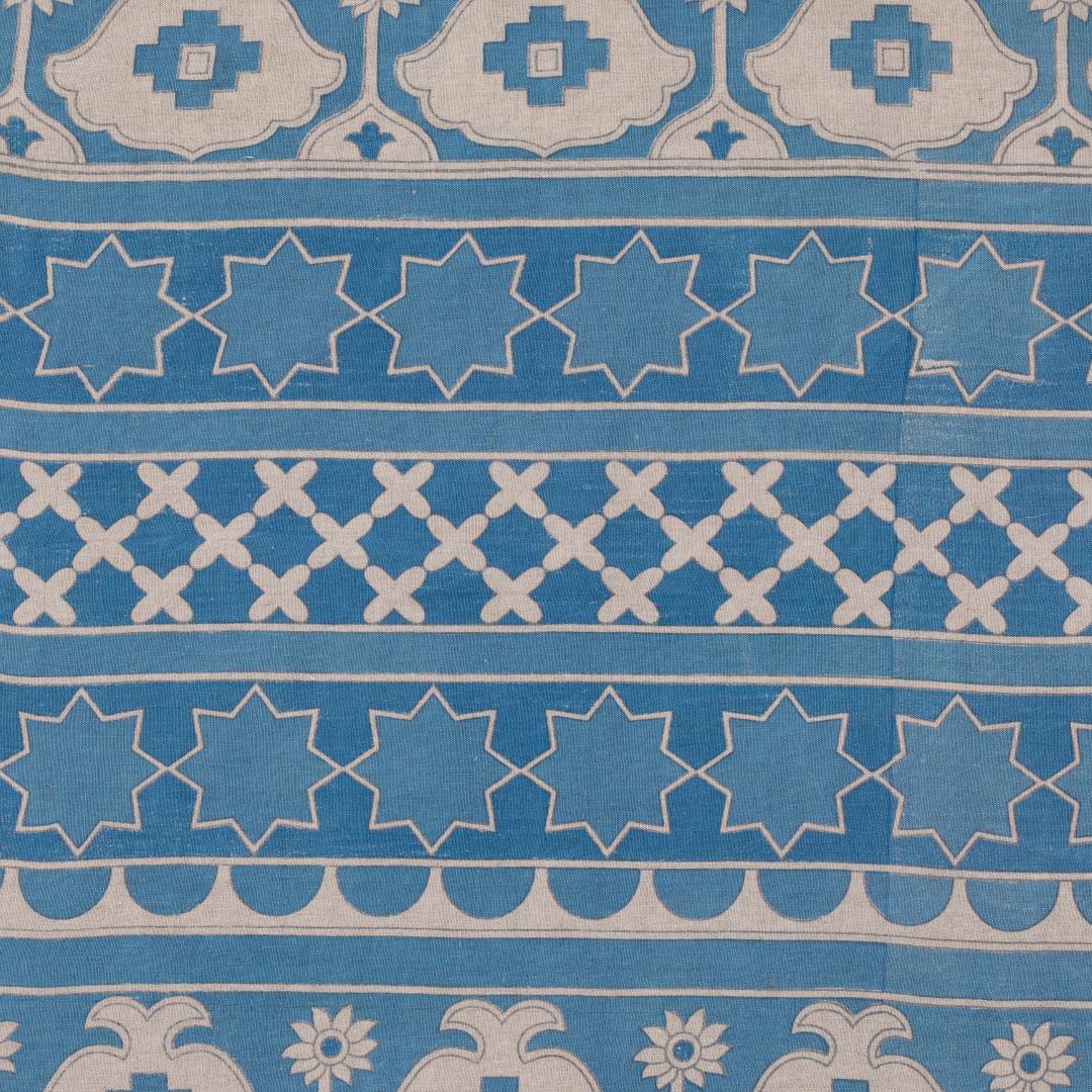 Detail of fabric in an intricate linear lattice print in cream on a blue field.