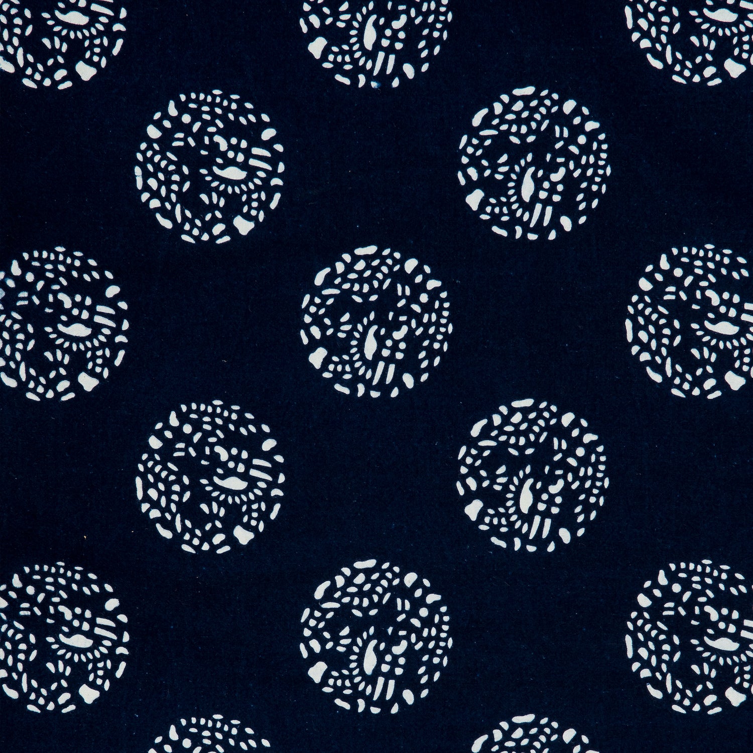 Detail of a printed cotton fabric in a repeating dotted pattern in white on an indigo field.