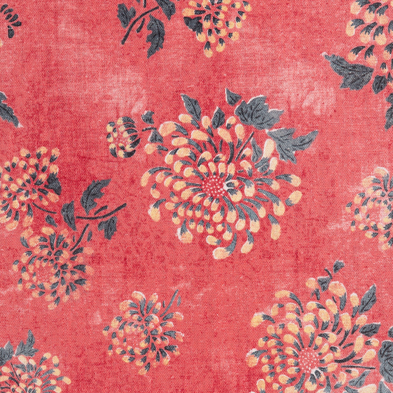 Detail of a printed linen fabric in a repeating floral pattern in shades of yellow and green on a red field.