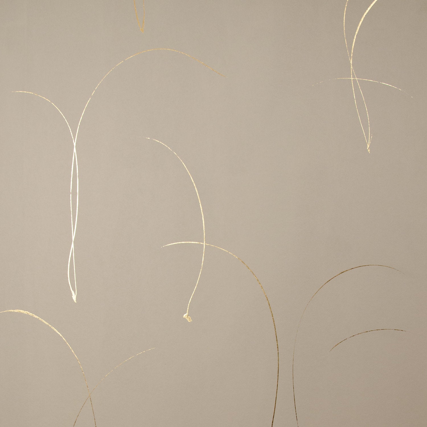 Detail of a wallpaper in an elongated paint splatter pattern in metallic gold on a cream field.