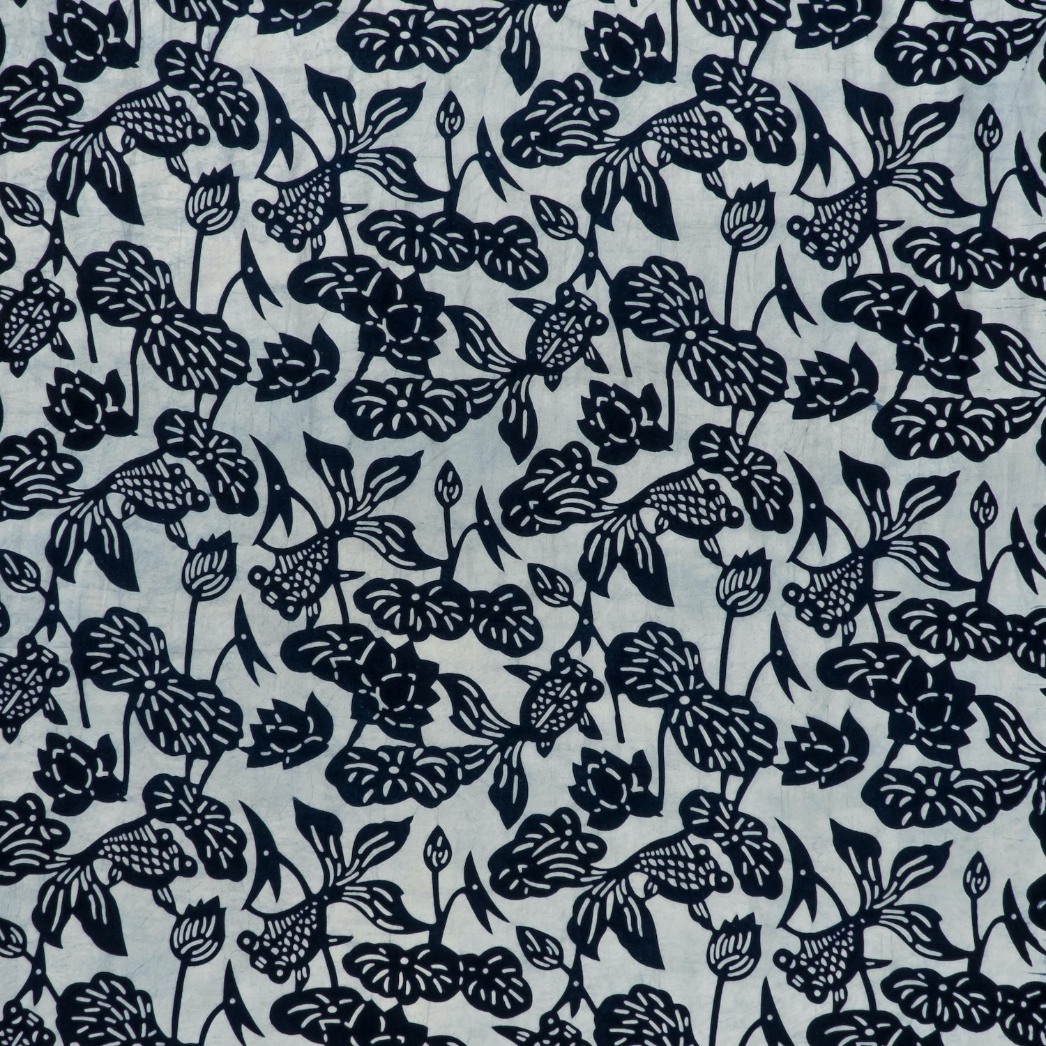 printed cotton fabric in a repeating fish and leaf pattern in indigo on a gray field.