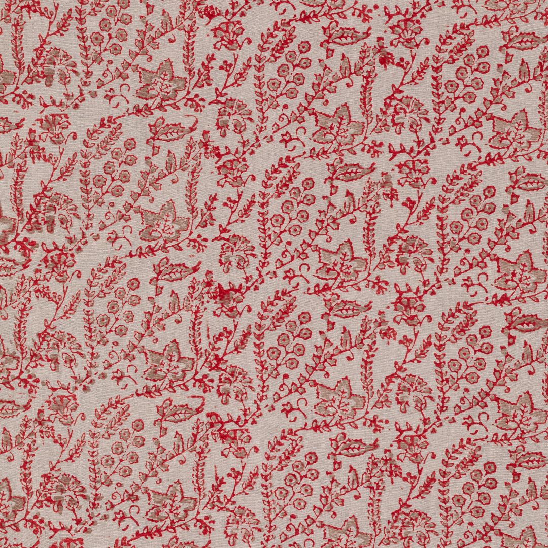 Detail of fabric in a dense floral print in red and tan on a cream field.