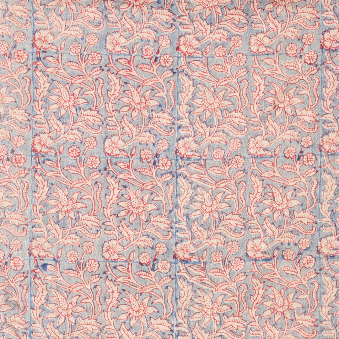 Detail of fabric in a floral block print in cream and red on a blue field.