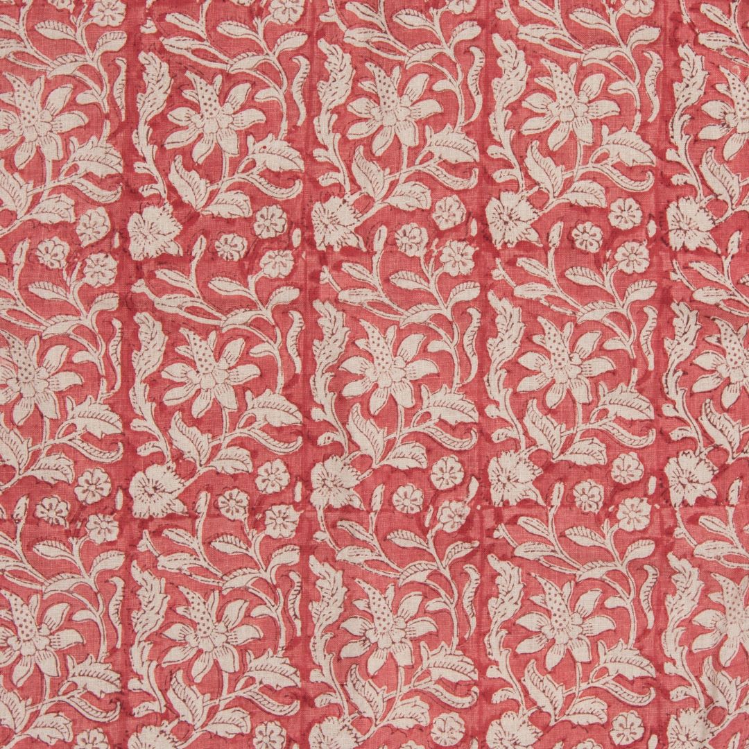 Detail of fabric in a floral block print in cream on a red field.