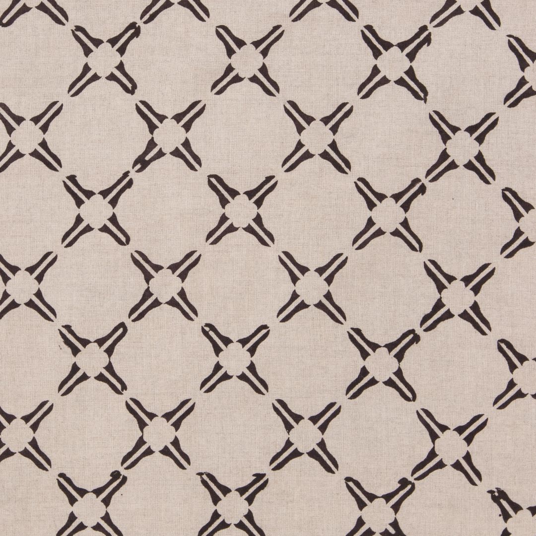 Detail of fabric in a geometric lattice print in black on a tan field.