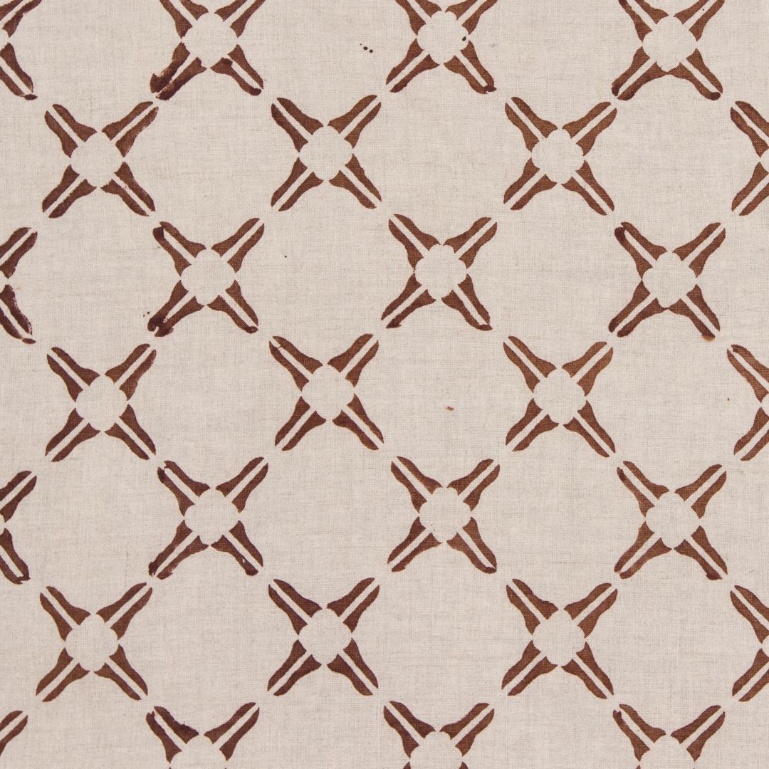 Detail of fabric in a geometric lattice print in rust on a tan field.