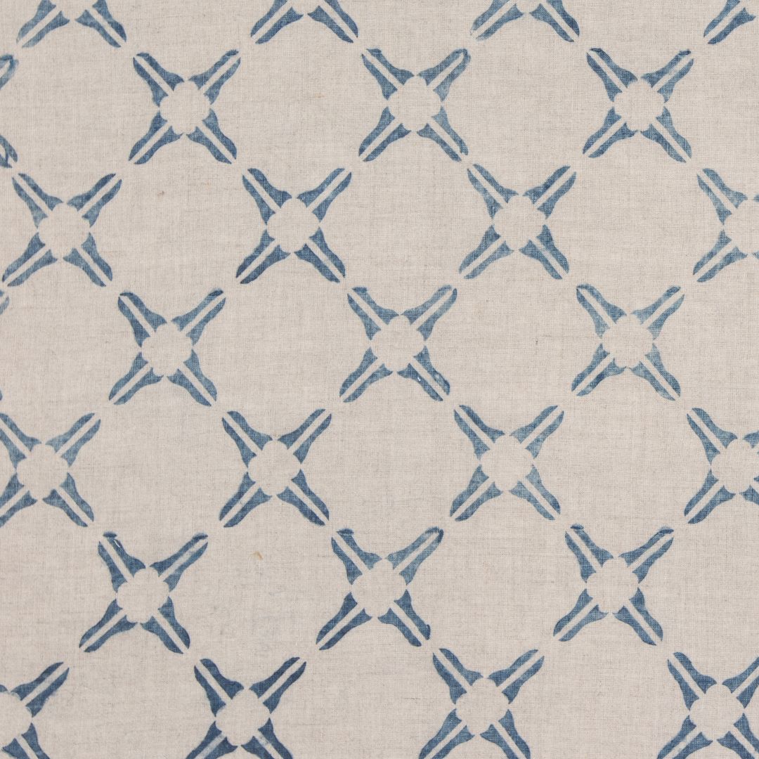Detail of fabric in a geometric lattice print in blue on a tan field.