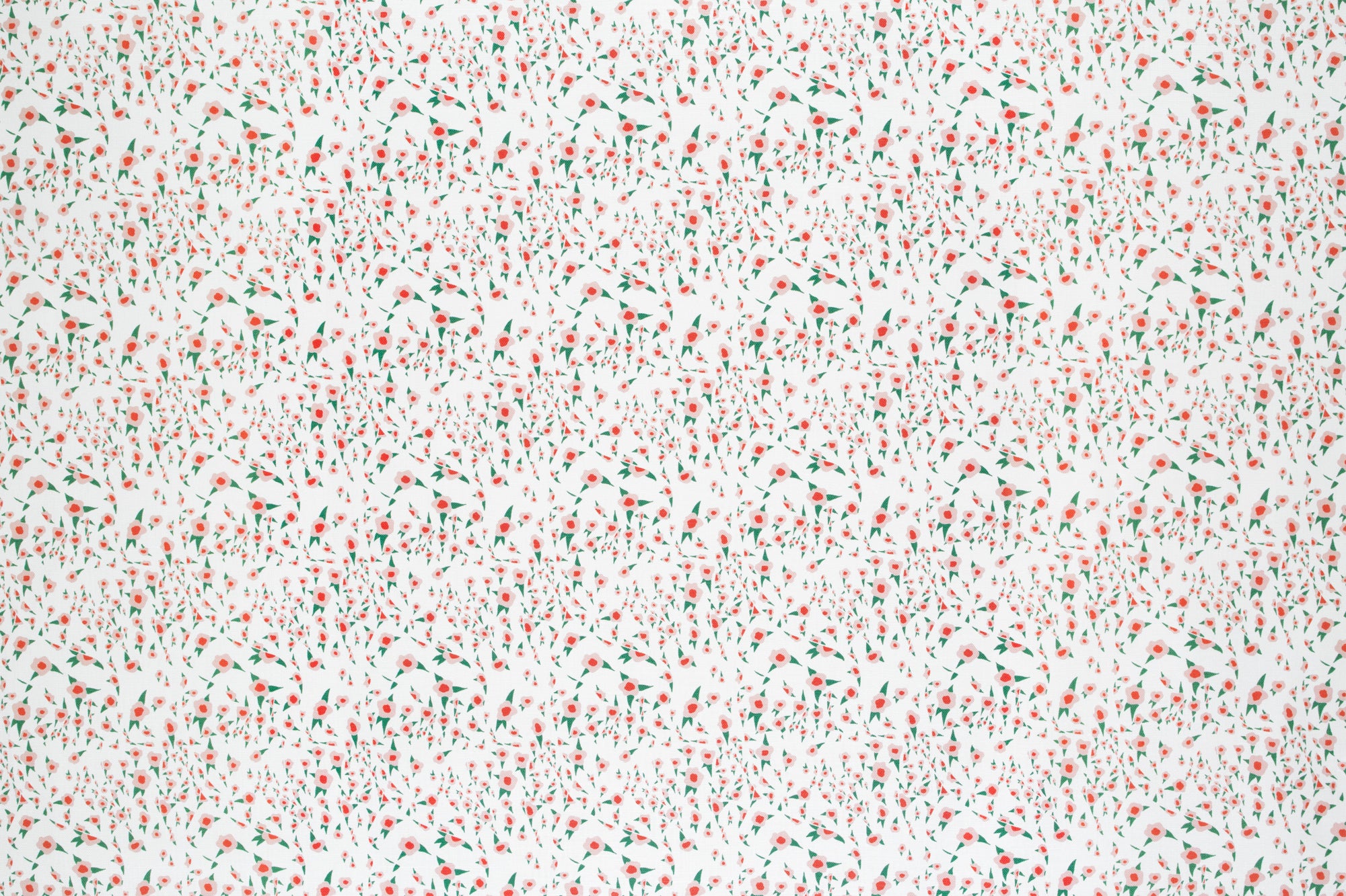 Detail of fabric in a small-scale floral pattern in pink, red and green on a cream field.