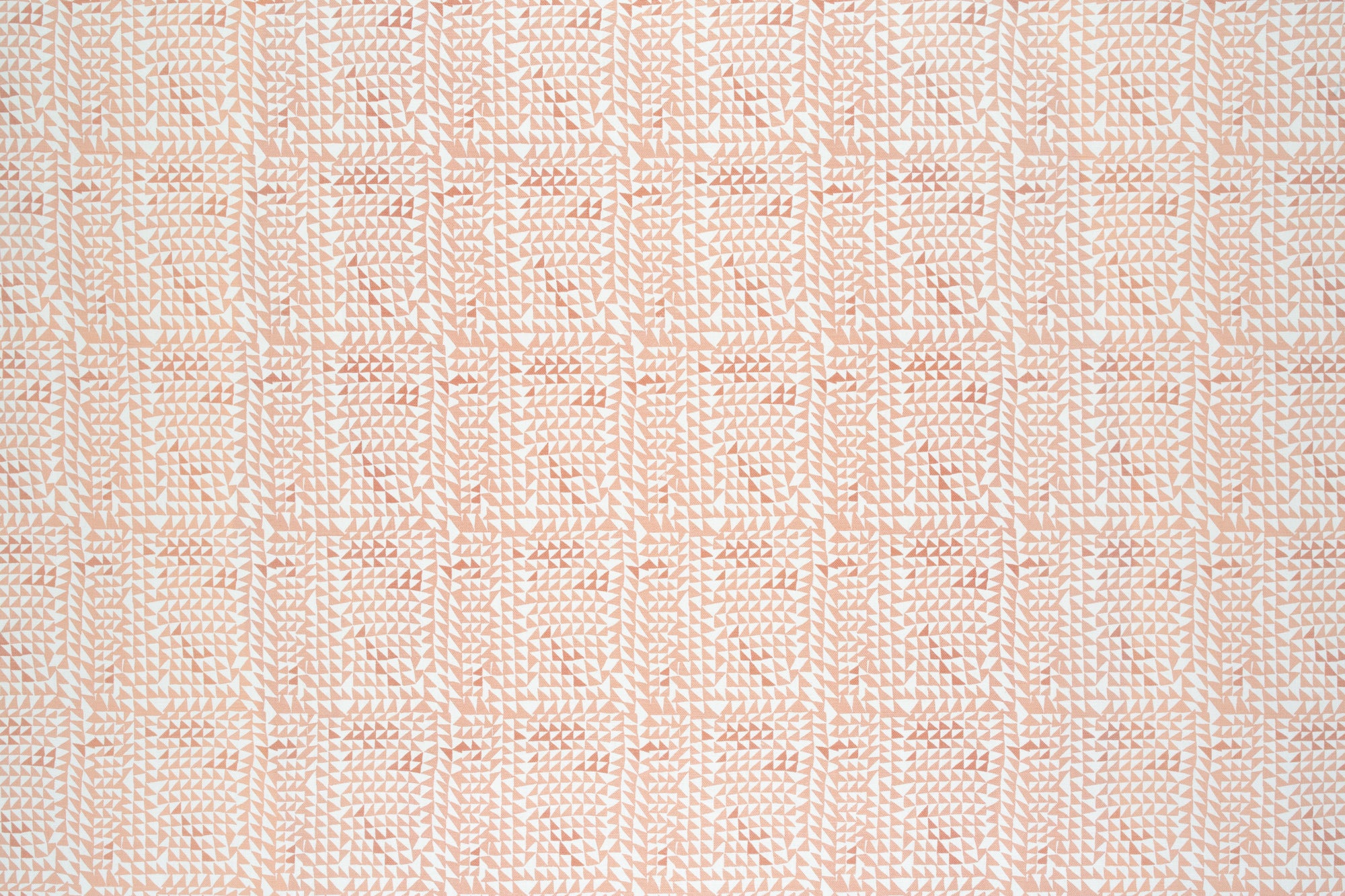 Detail of fabric in a dense triangle grid print in shades of pink and coral on a white field.
