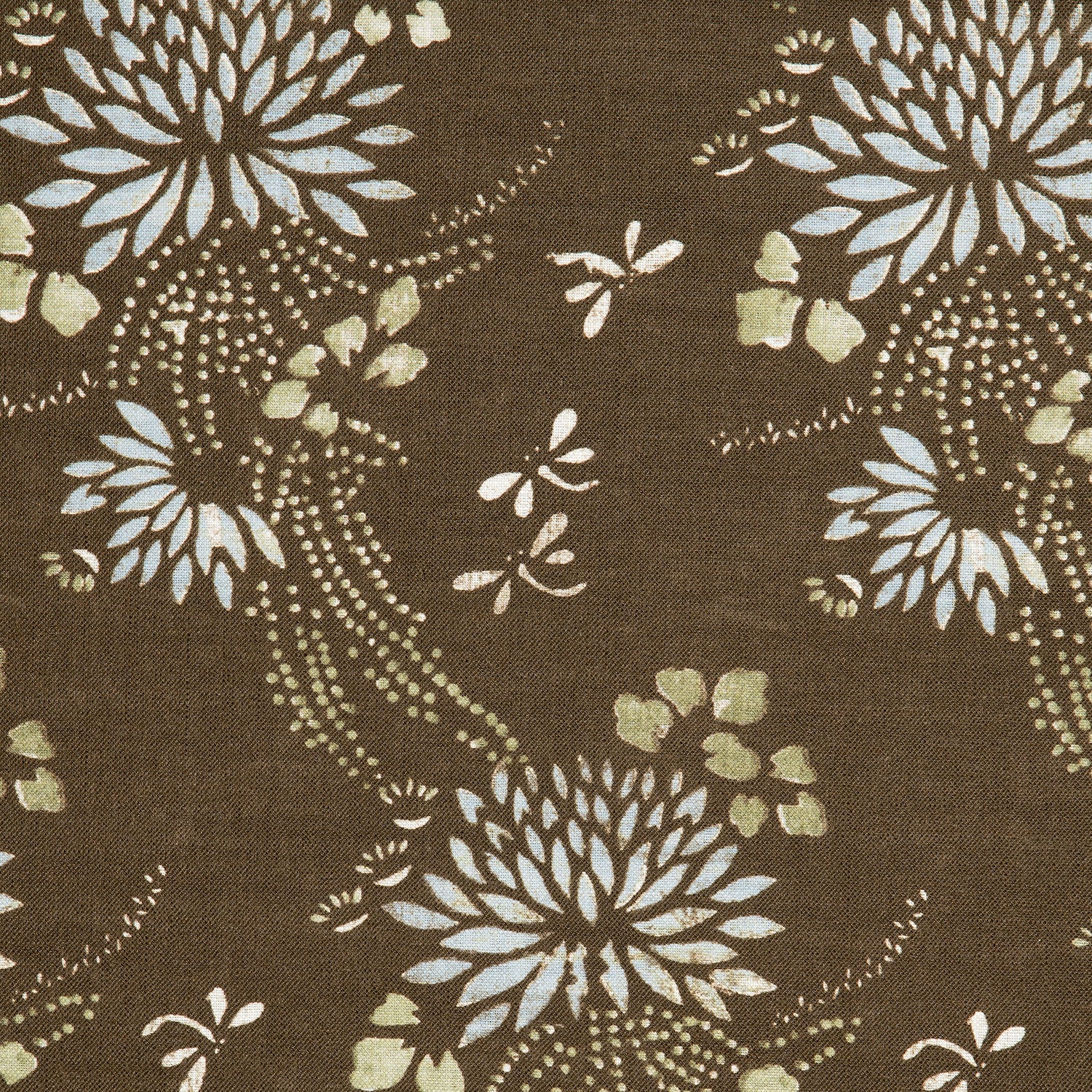 Detail of a linen fabric in a floral and dot pattern in beige and white on a brown field.